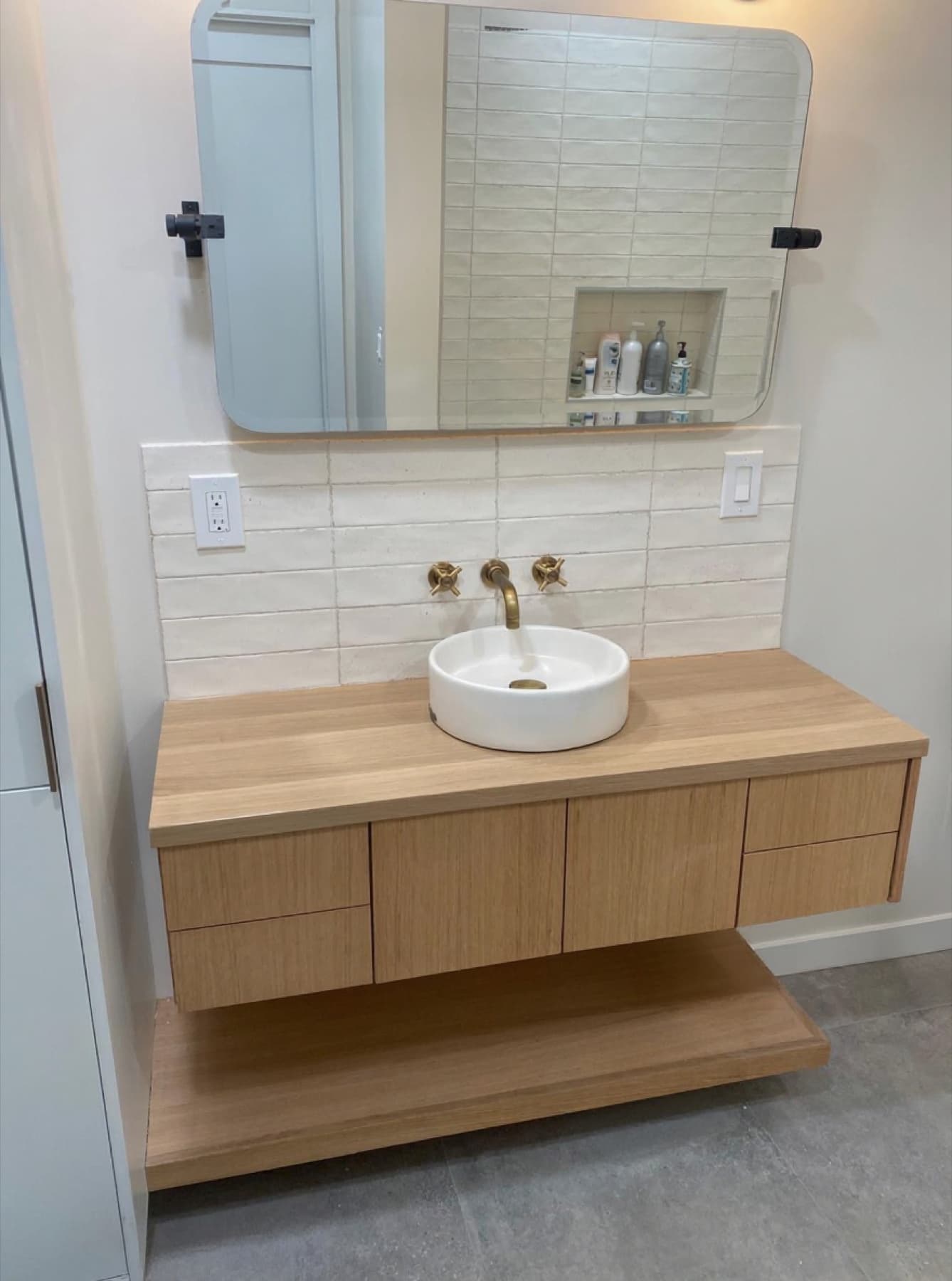 Floating oak vanity with vessel sink and brass cross handles
