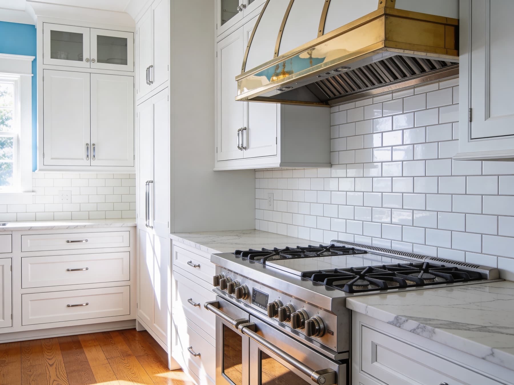 Range and brass-trim hood against subway-tile backsplash